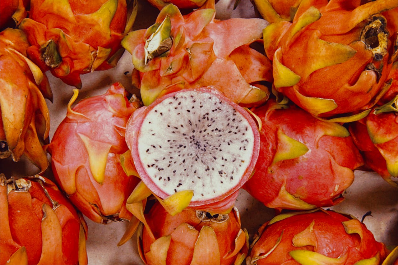 services-01 A vibrant overhead shot of fresh red dragon fruits, including a sliced piece revealing its white flesh and black seeds.